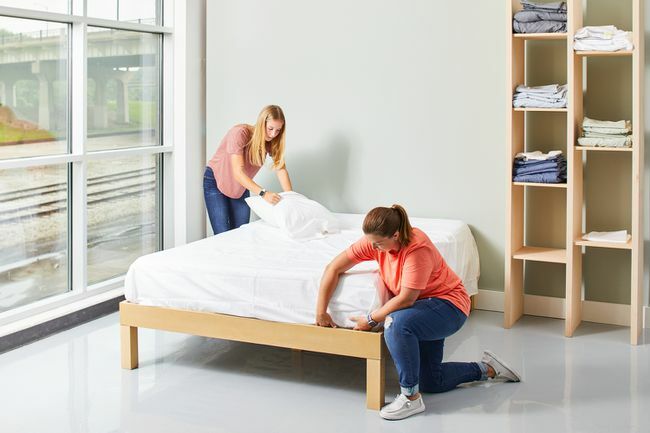 Zwei Frauen machen Bett mit weißen Laken